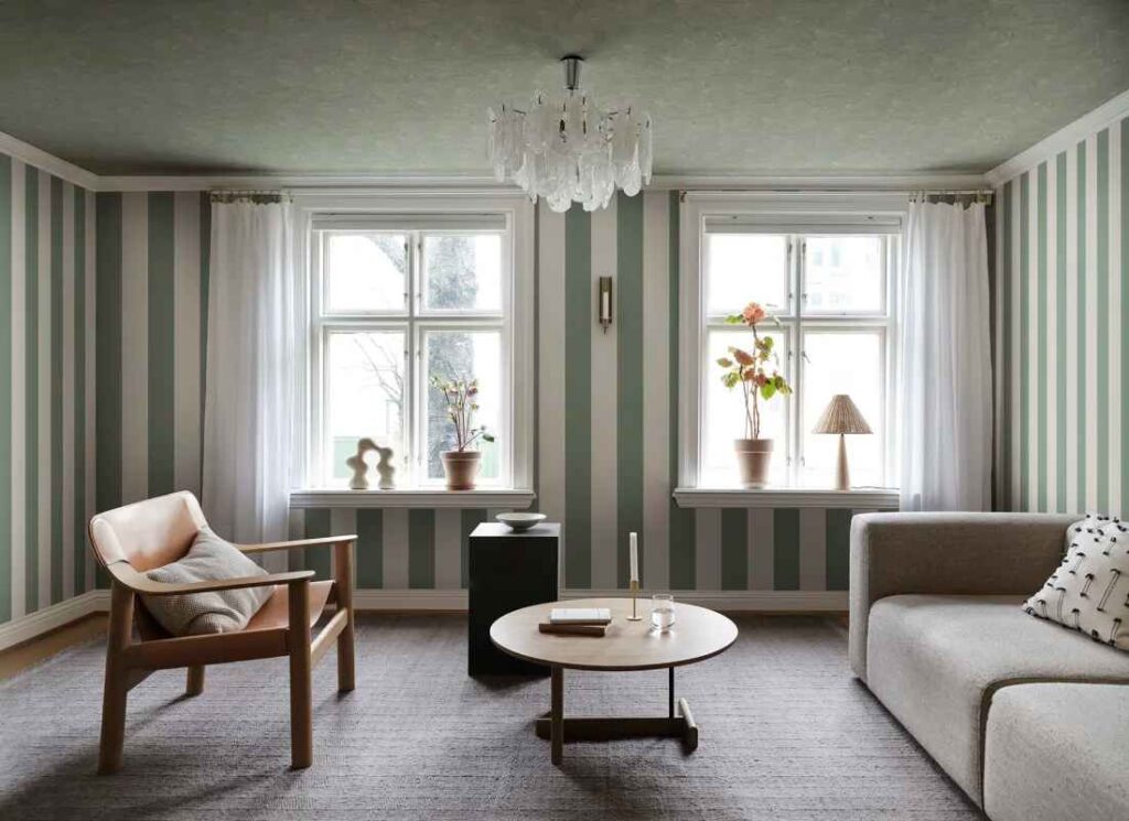 A sage green with striped wall and chair and wooden floor