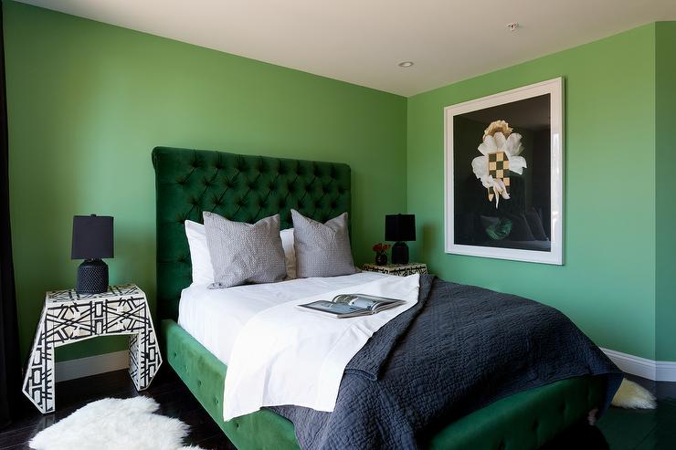 A green bedroom with emerald green bedding and white framed frame on the wall 