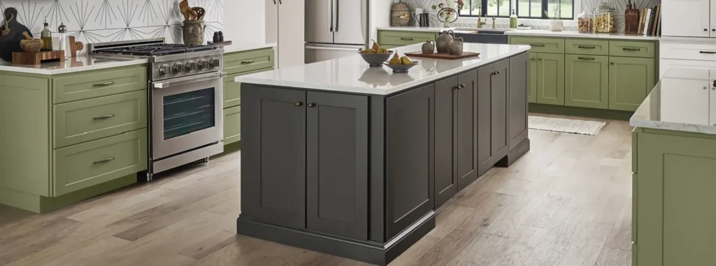 A sage green cabinets with grey island and wooden flooring