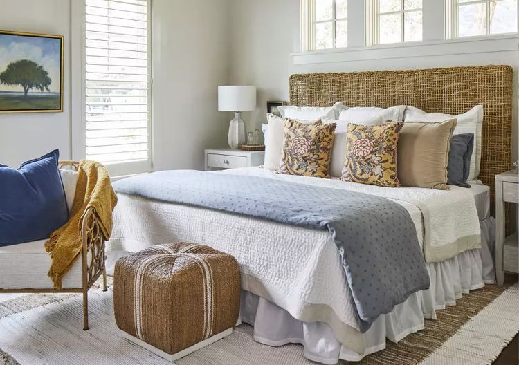 A bedroom with layered bedding and white blankets and pillow and white framed windows