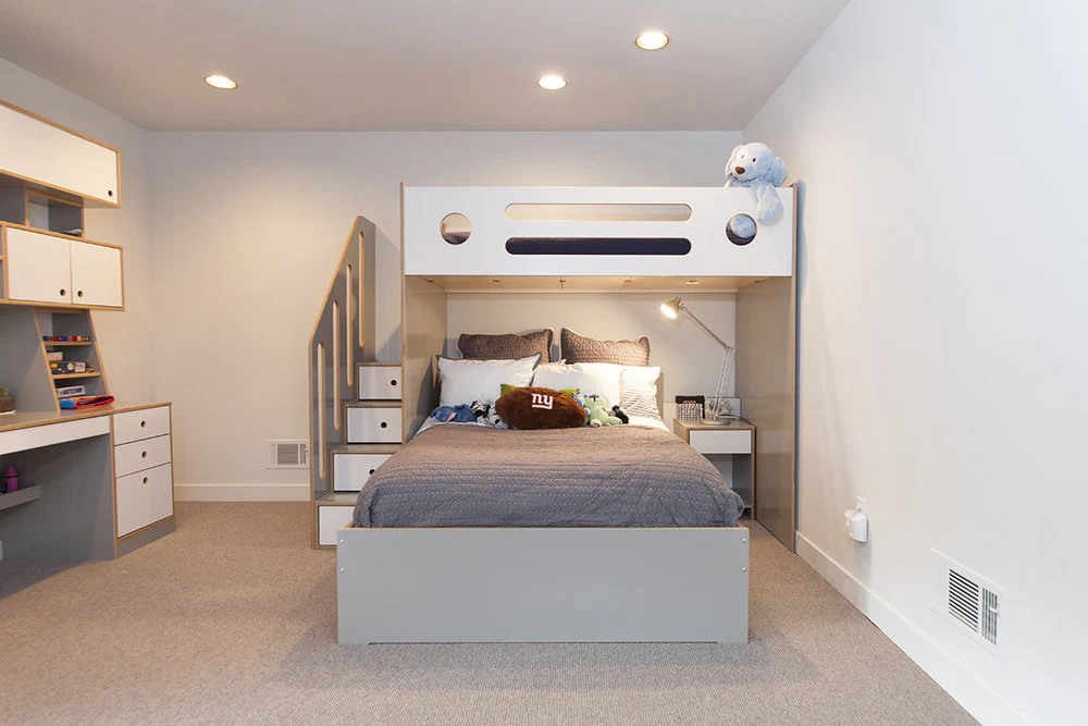 A bedroom with loft beds with built in shelves and warm lights 
