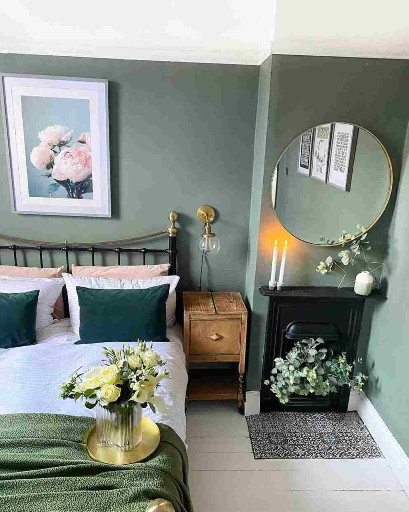 Green bedroom with mirror on the wall and wooden nightstand and white frames painting on the wall 
