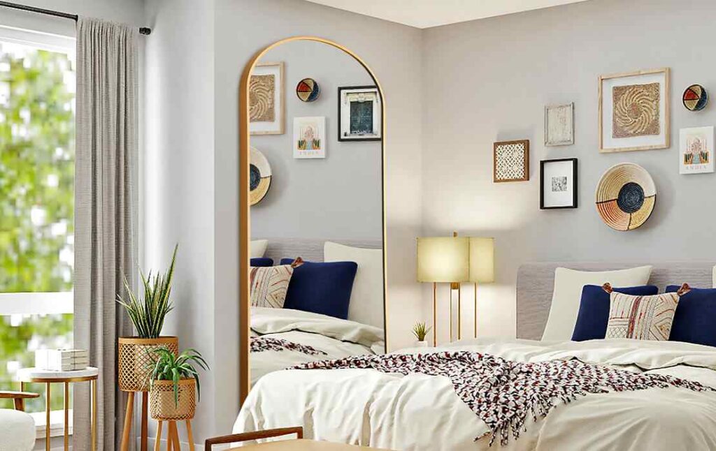 A bedroom with mirror on the wall and frames on the wall and bed