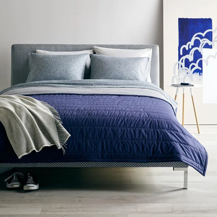 A navy quilt with light grey bed and wall