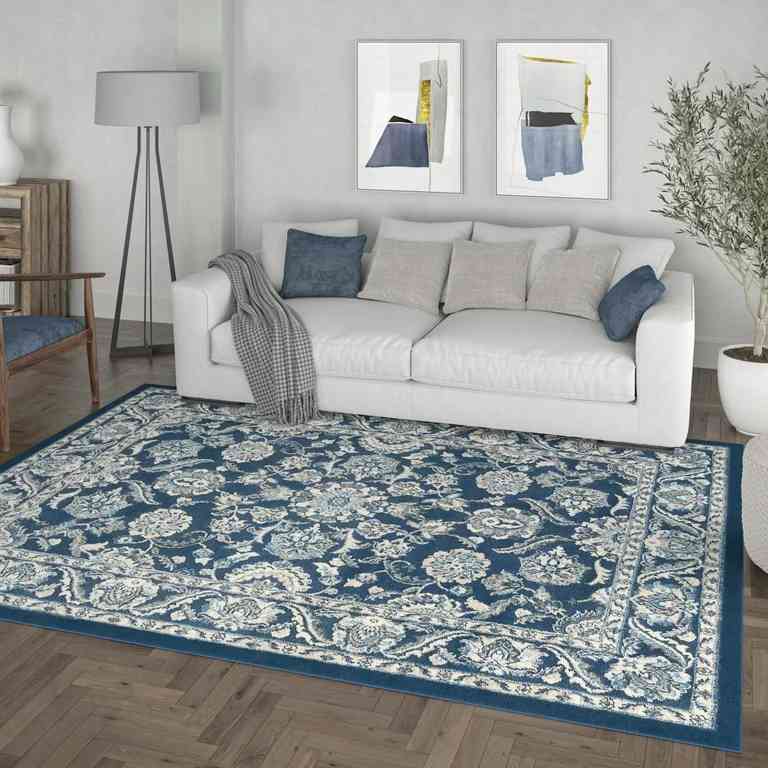 A living room with blue rug on the floor and sofa with cushion
