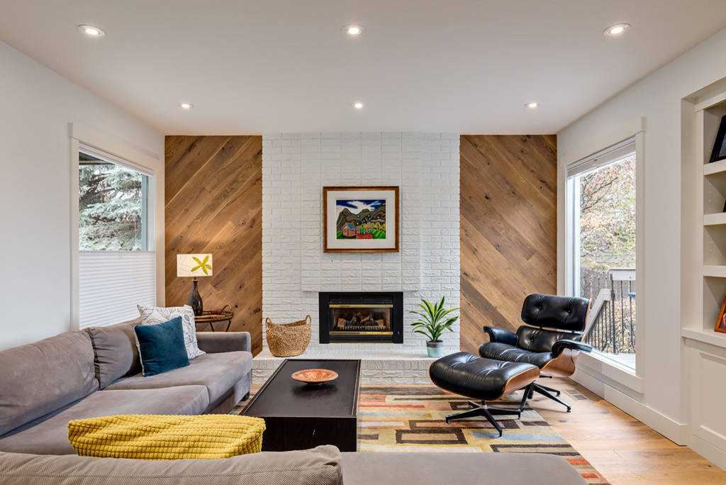 A mid century living room with wooden floor and brick fireplace