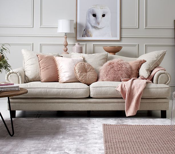 A beige living room with pink accents and wooden floor 