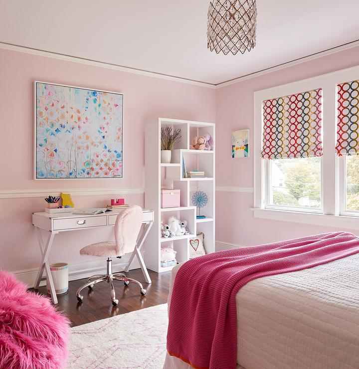A pink bedroom with white trim and study table with hairs