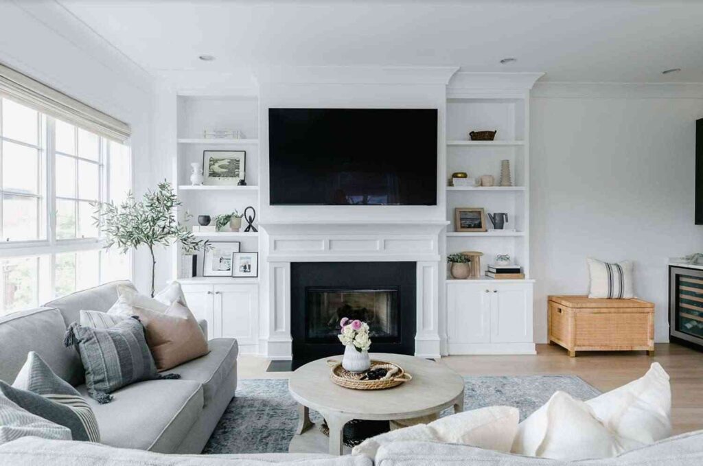 A living room with open shelves and fireplace and wooden floor