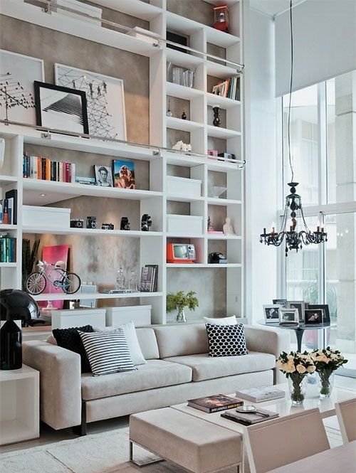 A small living room with shelves in display and wooden table and sofa