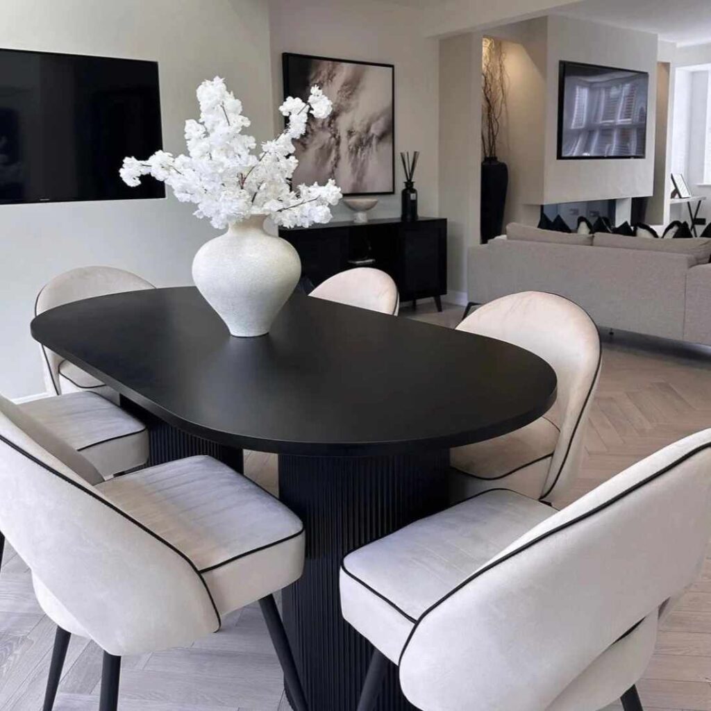 A small living room with oval shaped dinning table and vase on the table