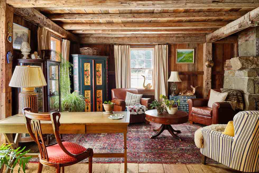 A vintage room with rug on wooden floor and white framed windows