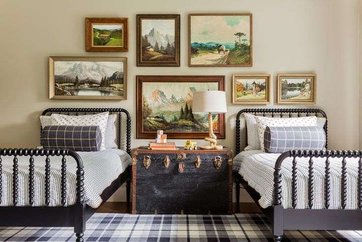 A bedroom with work art on the wall and iron framed bed 