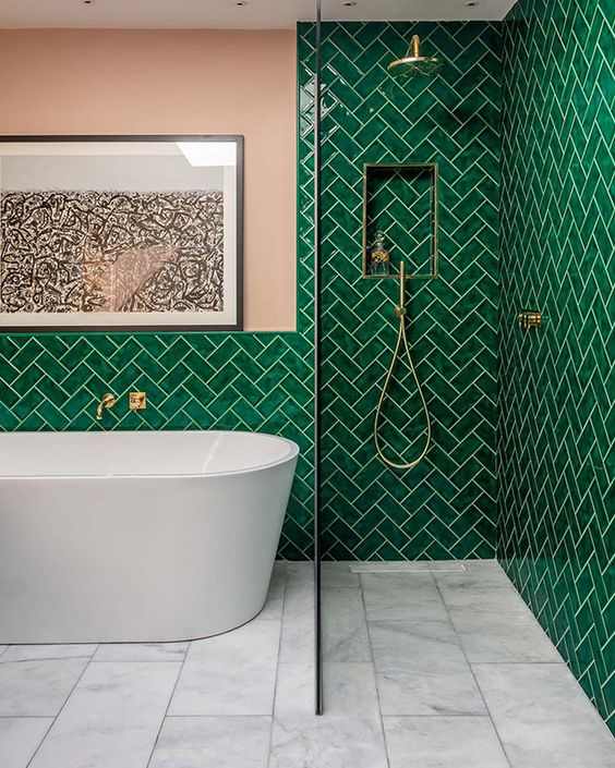 A pink and green bathroom with white bathtub and gold fixtures