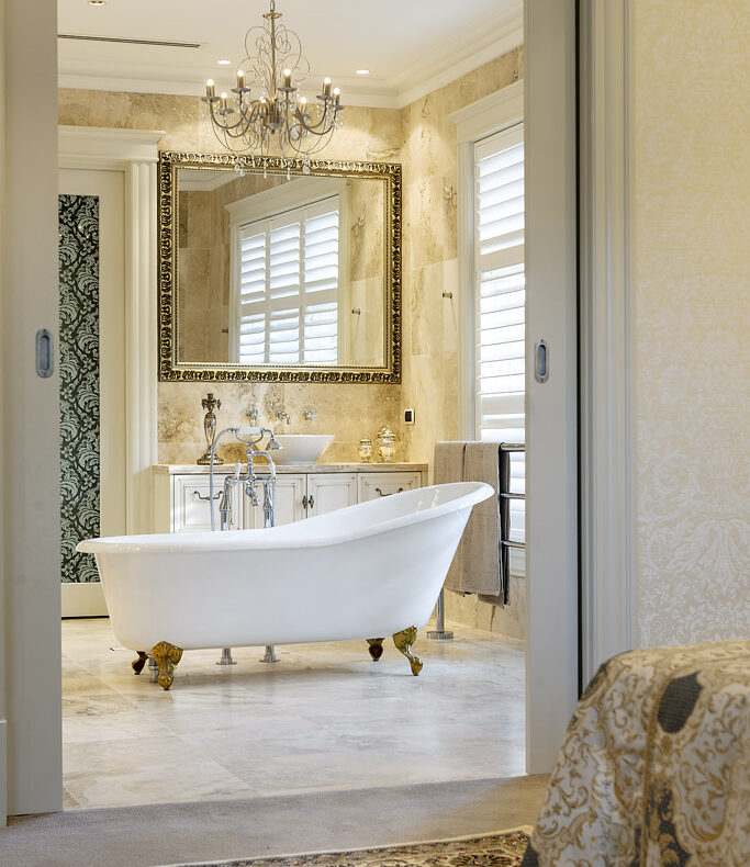 A bathroom white bathtub with gold clawfoot  and mirror on the wall 