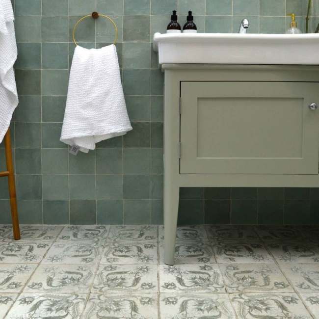 A sage green bathroom with green vanity with white sink