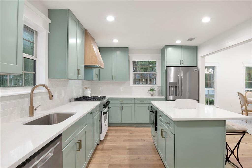 A sage green with white quartz countertop an wooden floor and white walls