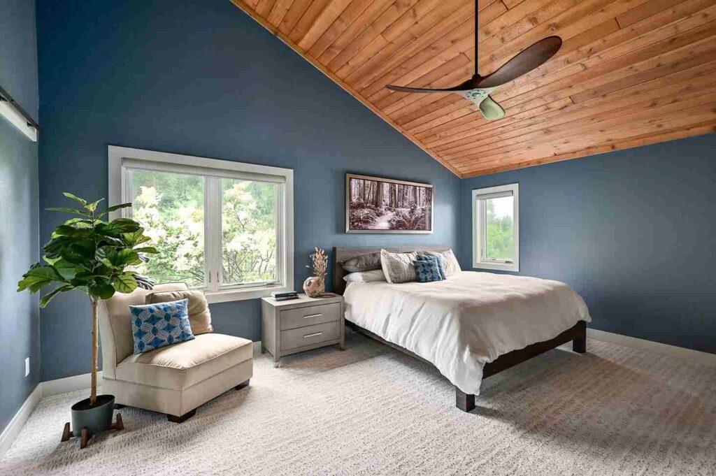 A wooden celling in blue bedroom with widows and sofa with cushion