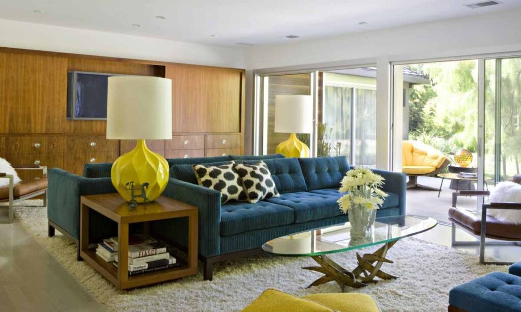 A mid century living room and blue sofa and wooden wall