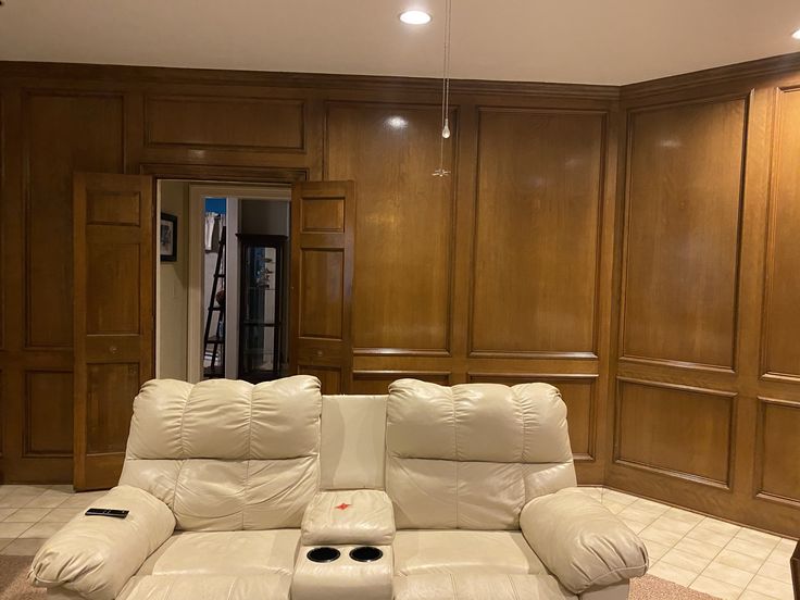 A living room with wood panel walls and sofa and celling lights