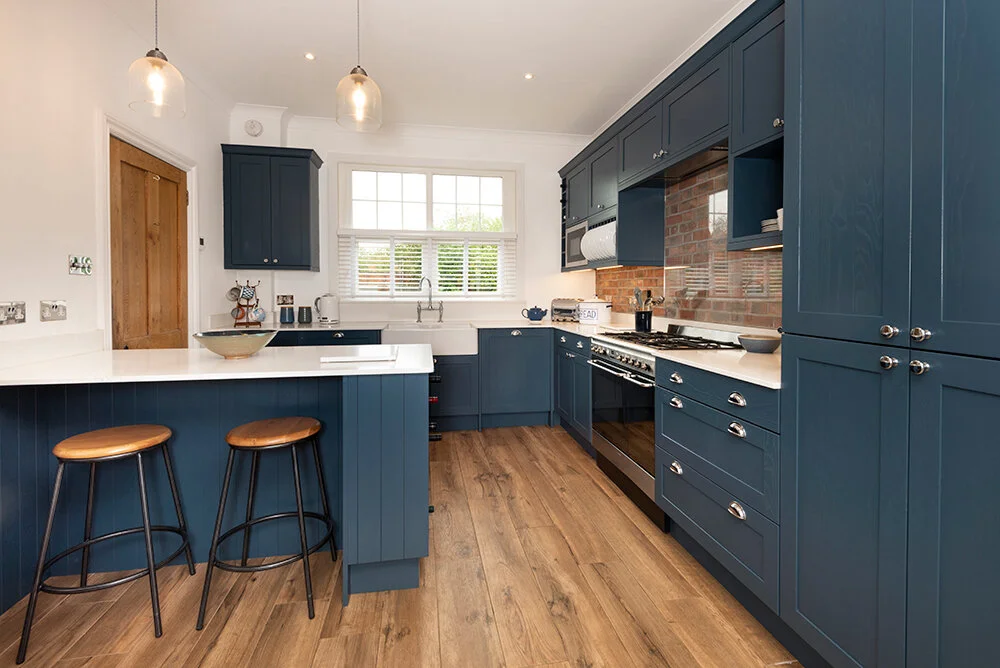 A wooden floor on blue kitchen and lights above the wall