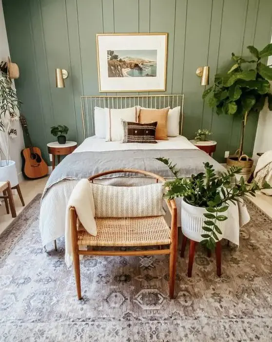 A sage green bedroom with woven rattan furniture and lights on the wall
