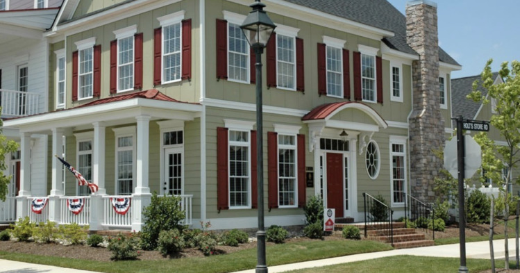 A sage green house with red shutter and white trim 