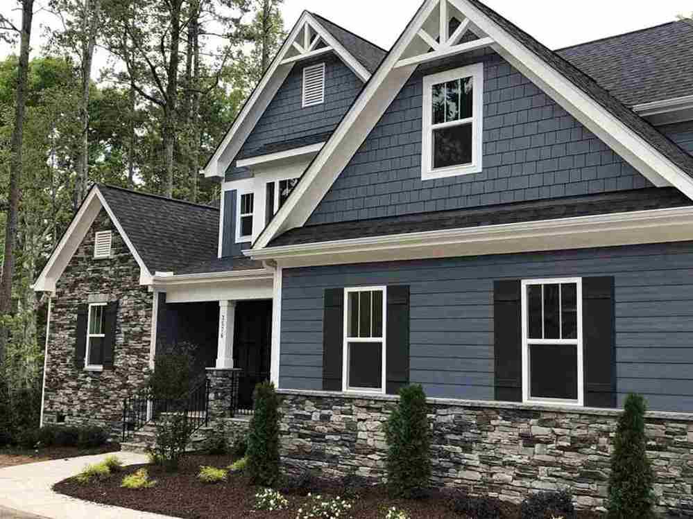 A dark blue house with white windows and with white gable roof 