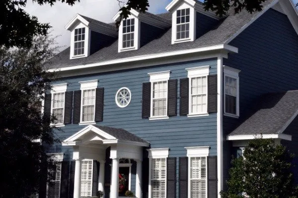A Colonial-style blue house with black trim and shutter 