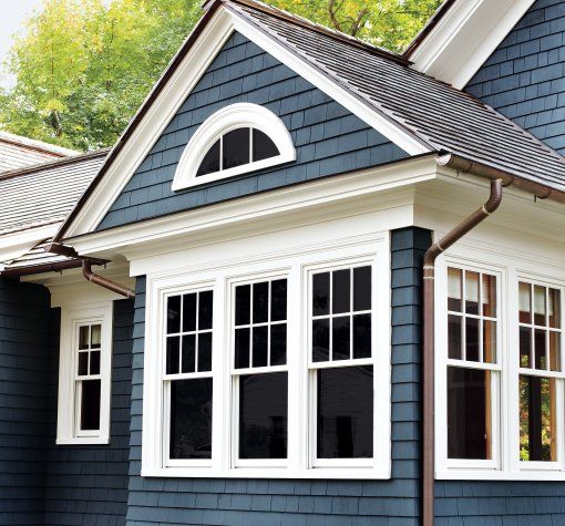 A blue house with white trim and copper gutters and windows 