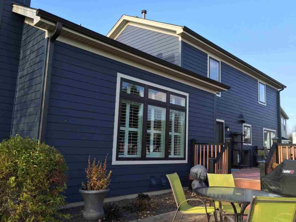 A blue house with black trim and. garen outside of the house 