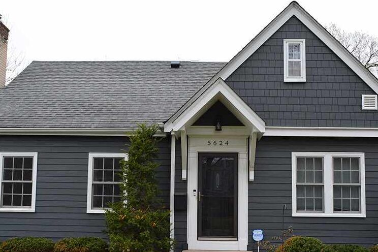 A grey house with dark charcoal shingles and windows