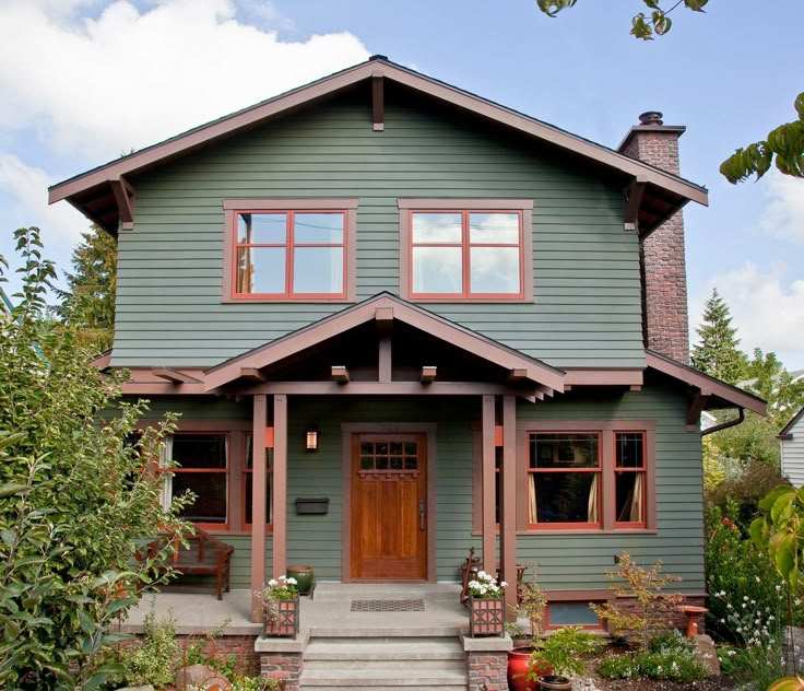 A green house with brown trim and wooden door and windows 