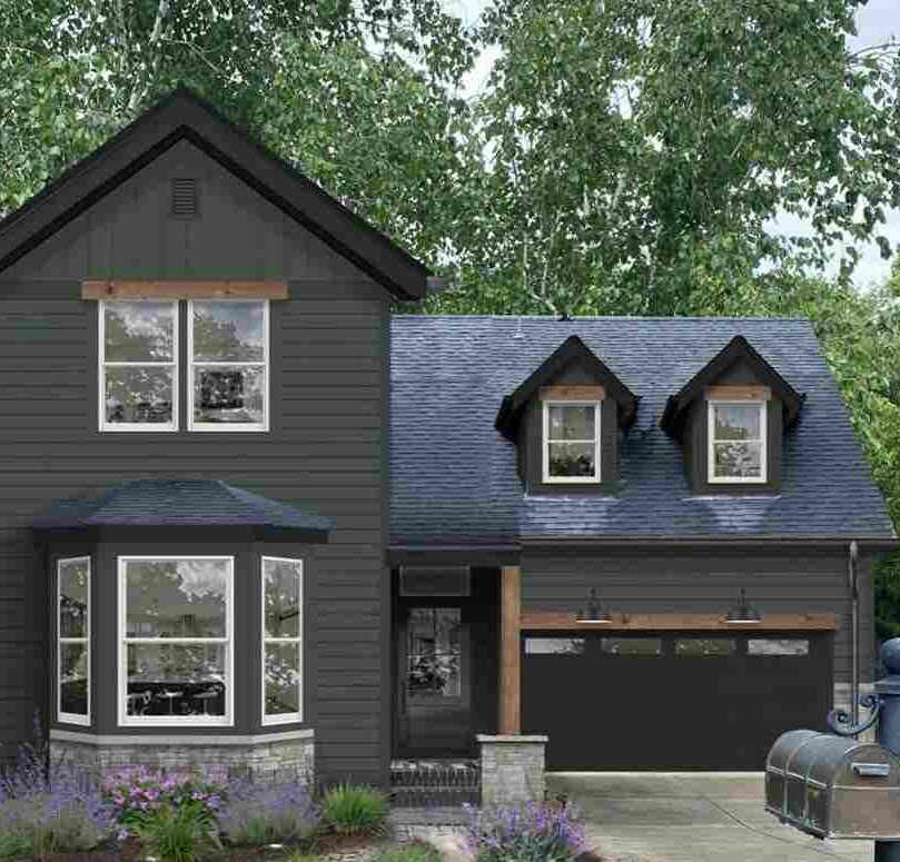 A dark sidling in olive green house and white trim 