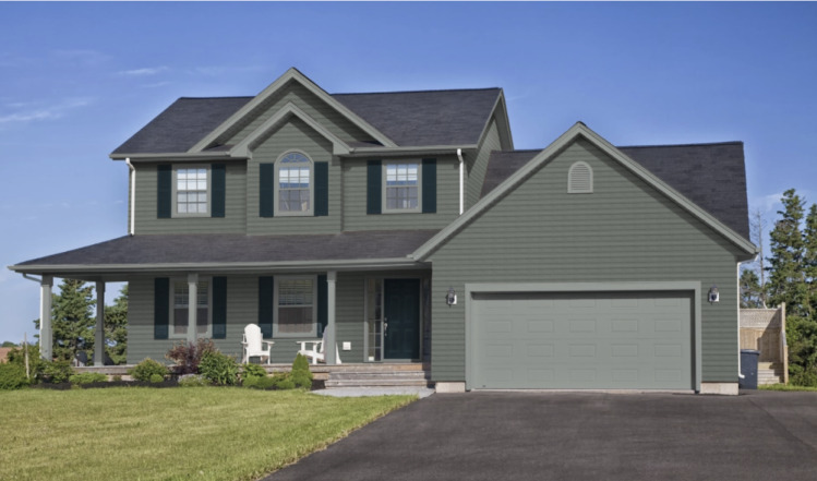 A sage green house with grey accents and white gutter 