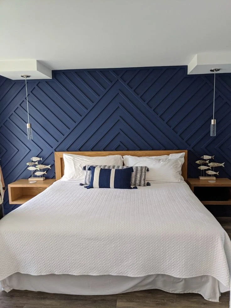 A navy bedroom with accents wall and white sheet and pillow