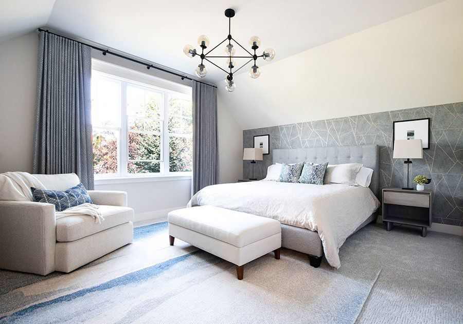 A white and grey bedroom with grey curtain and sofa and cushion on it 