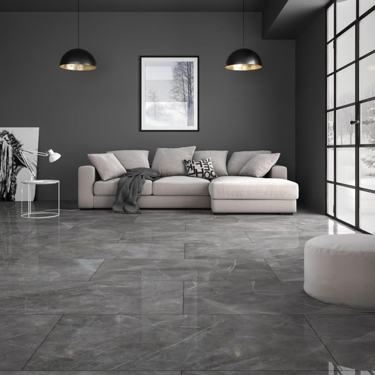 A grey living room with grey marble flooring and beige sofa with side table and lamp on it 