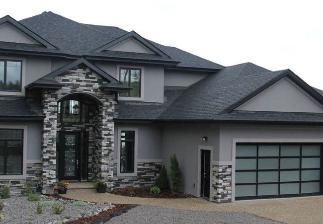 A light grey house with black roof and stone entryways 