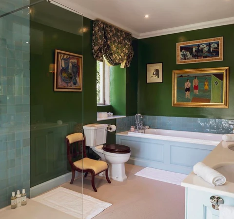 A green bathroom with white bathtub and frames on the wall