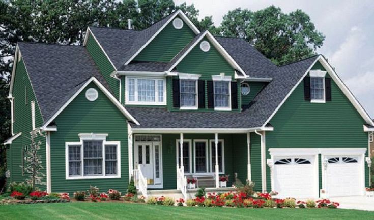 A green house with white trim and white garage door and black shutter 