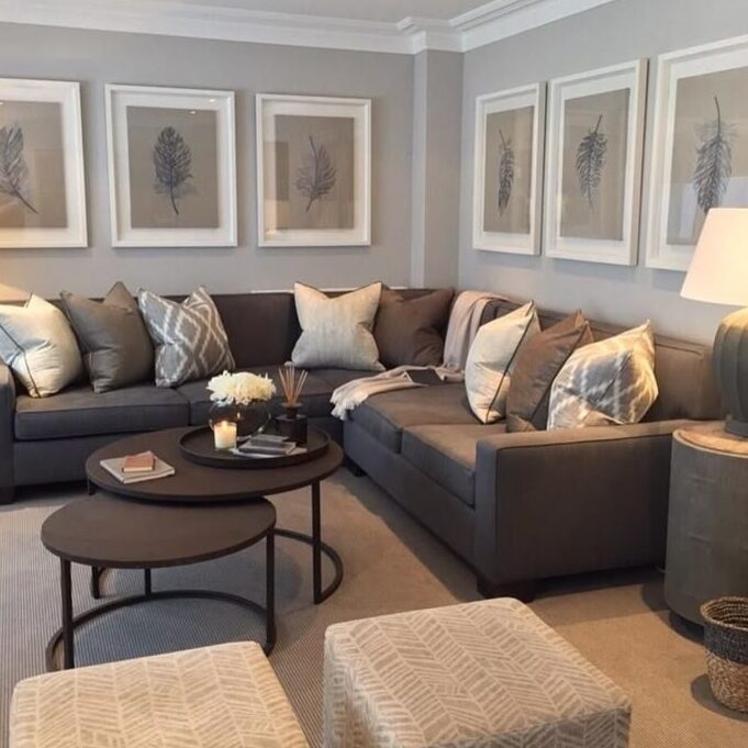 A grey wall with brown sofa and table and white framed frame