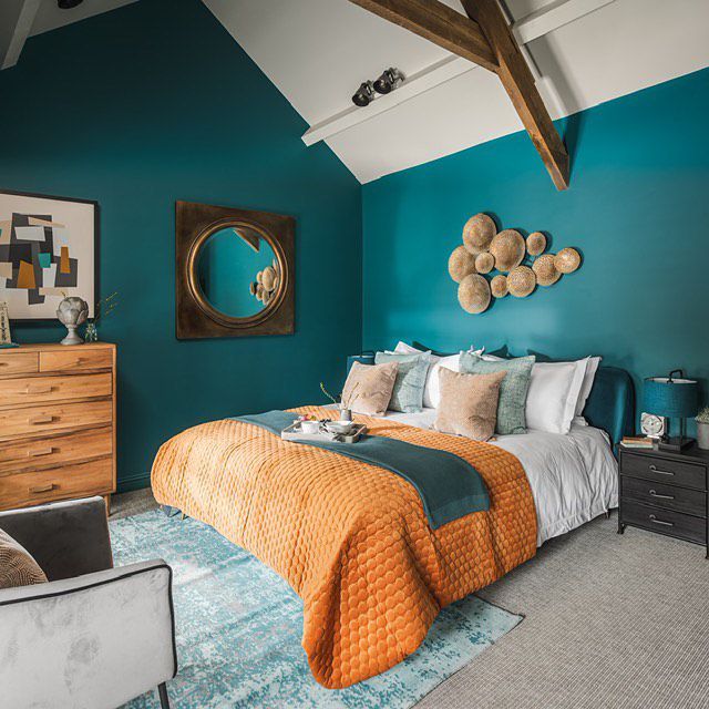 A teal blue bedroom with vintage mirror on the wall and wooden floor 