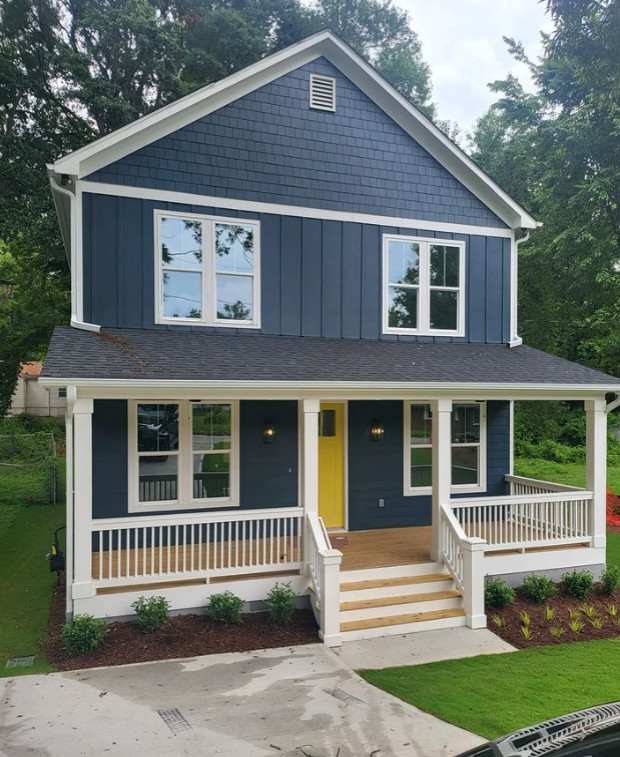 A navy blue house with white trim and white pillar amd wooden porch