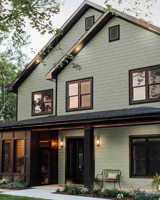 A green house with black windows and lights on the wall 