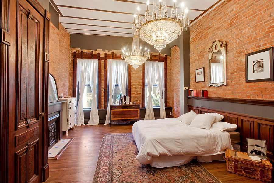 A terracotta bedroom with white bed and pillow and wooden floor and ornate chandelier