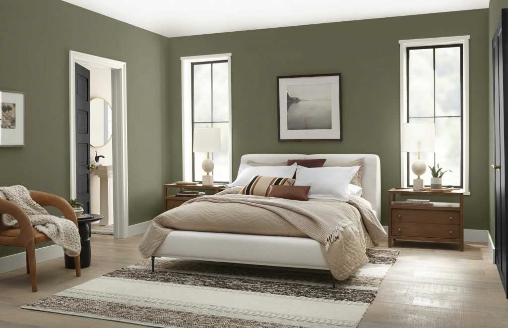 A olive green bedroom with windows and wooden floor and wooden nightstand 