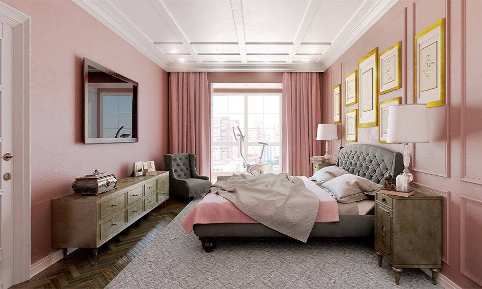 A pink bedroom with white celling and gold frames on the wall