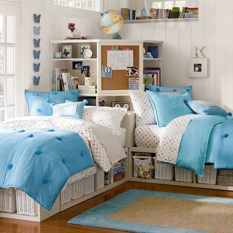A small bedroom with storage and blue blanket and pillow 