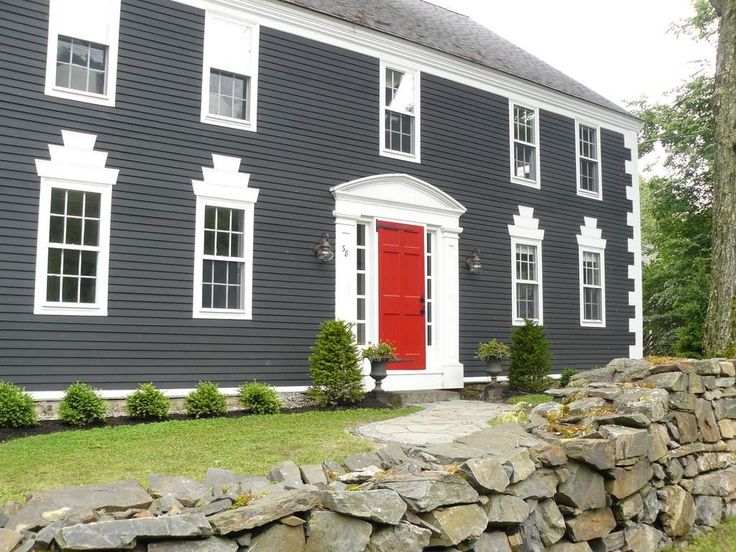 A grey house with white trim and red door 